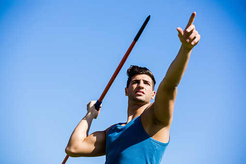 Determined athlete about to throw a javelin in the stadium