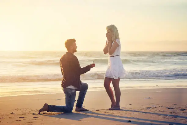 Shot of a young man proposing to his girlfriend on the beach