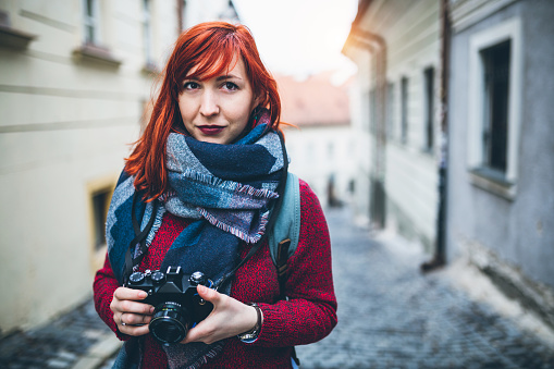 Beautiful young tourist on the street of city, walking with photo camera