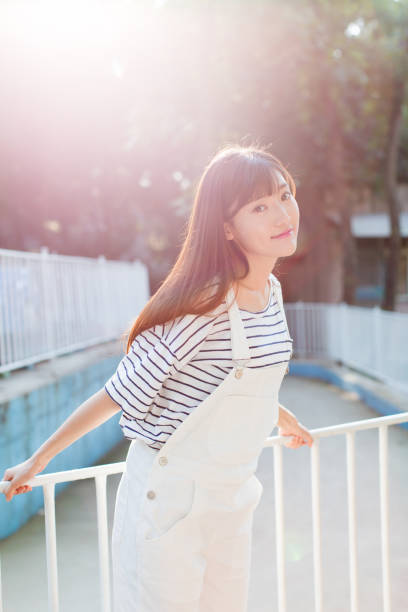 istock young pretty girl leaning on white railing against sunlight 661443124