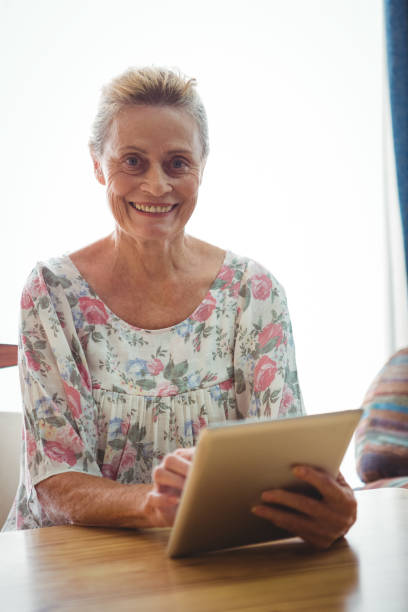 istock Senior woman looking at the camera using a digital tablet 661443324