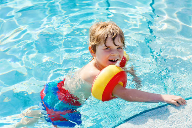 istock Happy little kid boy having fun in an swimming pool 661444322