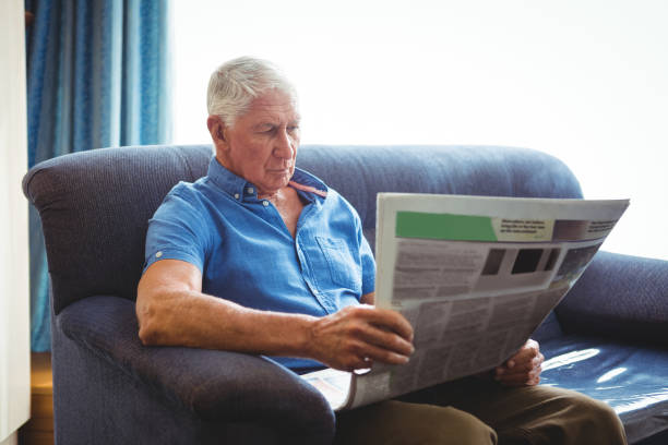 istock Senior man seated on a sofa reading 661446920