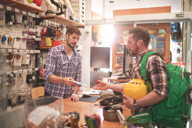 Male customer is standing in sports and outdoor equipment store at the cash register and buying new items.
