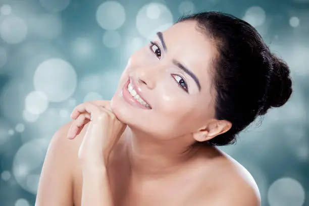 Closeup of beauty model with natural skin smiling at the camera on blur background