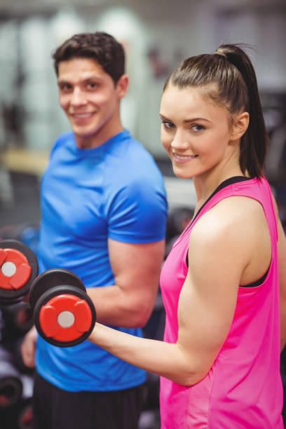 istock Woman lifting dumbbells with her trainer 661467160