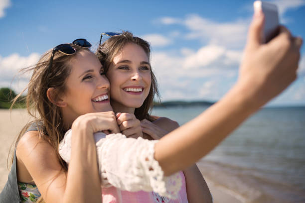 istock Two beautiful female friends taking selfie on beach 661477324