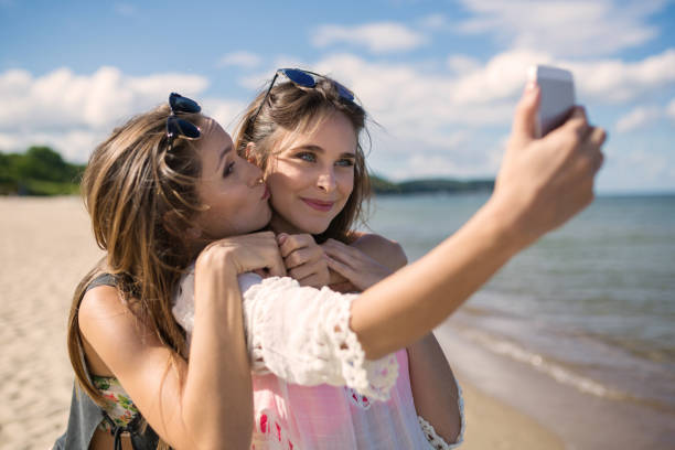 istock Two beautiful female friends taking selfie on beach having fun 661480856