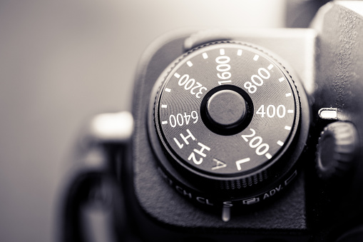 Close up macro image of the ISO sensitivity dial on an old, vintage rangefinder camera. We can also see the bracketing exposure dial. Horizontal toned image with copy space.