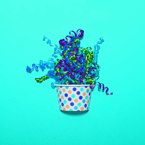 istock Multicolored confetti explosion from cup on blue background - Minimal flat lay design 661515898