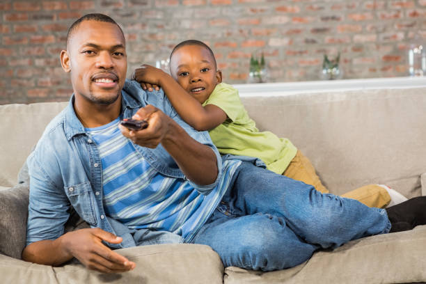 istock Father and son watching tv together on the couch 661537872