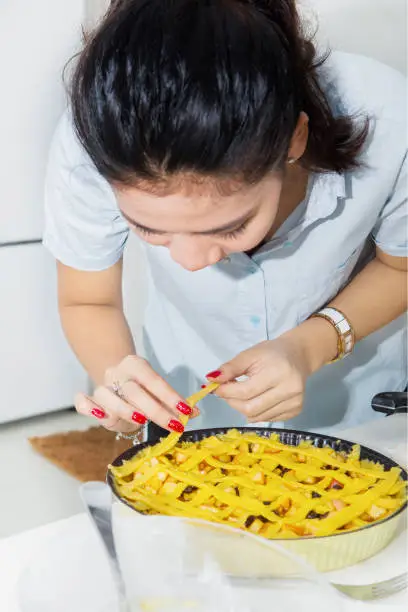 Picture of beautiful woman preparing for apple pie while putting pie dough on base pastry