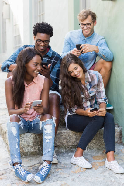 istock Friends sitting together using mobile phone 661539654