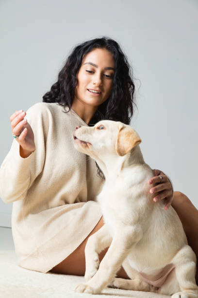 istock Lady sitting on the floor with her Labrador puppy 661546382