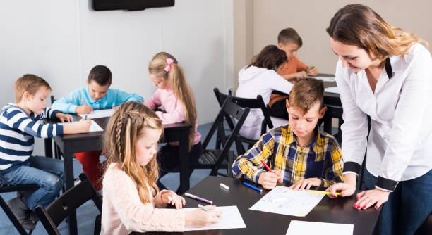istock Teacher and elementary age children drawing at class 661580560
