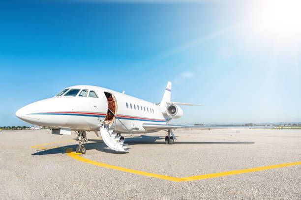 Airplane & boarding stairs Horizontal color image of luxury airplane for private flights stationary on airport runway against blue sky. Private jet is ready for boarding with open vehicle door - boarding stairs. No people shot, front view composition and space for copy. flight of steps stock pictures, royalty-free photos & images