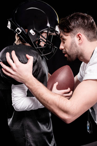 istock Side view of trainer instructing boy american football player 661609642