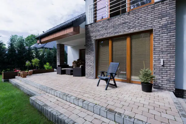 Small concrete terrace with furnitures in modern house with brick elevation