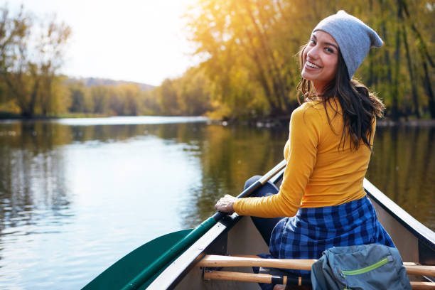 Join me for a gentle paddle out on the lake? Portrait of a young woman going for a canoe ride on the lake kayaking stock pictures, royalty-free photos & images