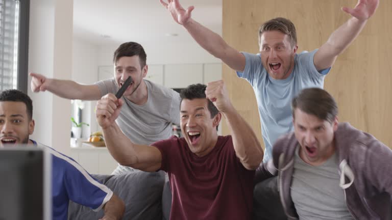 Men watching a football match and celebrating a goal