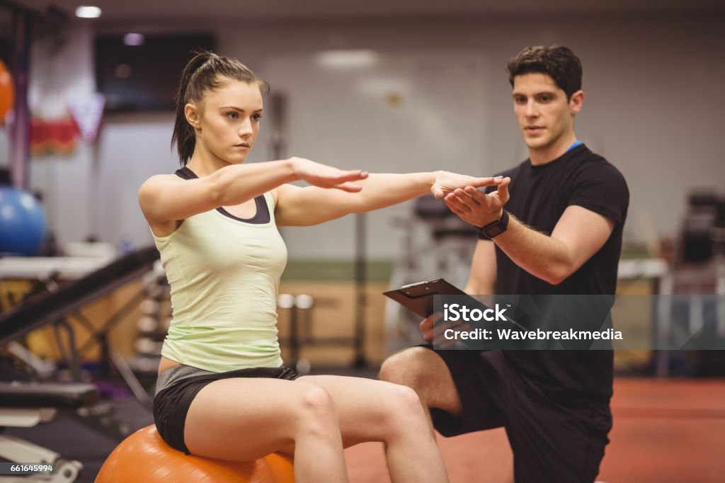 Fit woman working out with trainer Fit woman working out with trainer at the gym Fitness Instructor Stock Photo