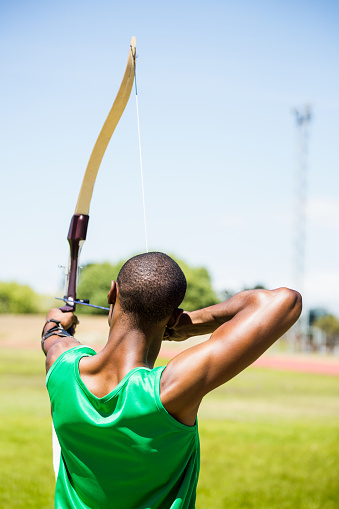 Rear view athlete practicing archery in stadium