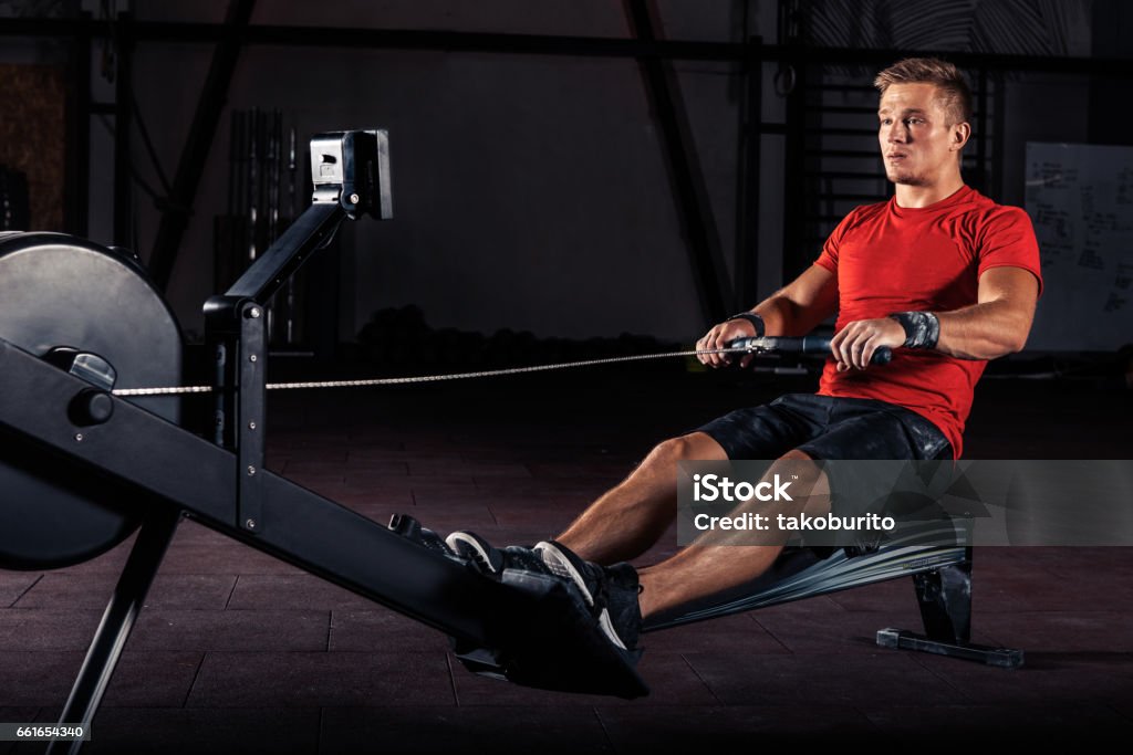 young man using rowing machine in the gym Fitness young man using rowing machine in the gym Rowing Stock Photo