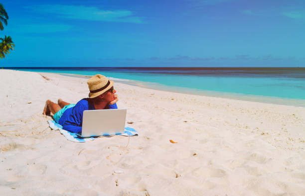 istock man with laptop on tropical beach 661687118
