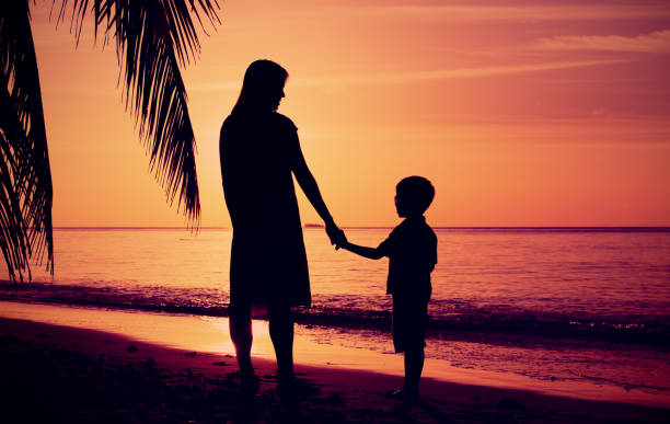 istock mother and son walking on sunset beach 661691846