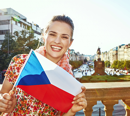 The spirit of old Europe in Prague. Portrait of smiling modern woman on Vaclavske namesti in Prague, Czech Republic showing flag