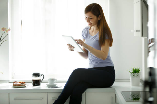 istock Smiling young woman using tablet at home 661749140