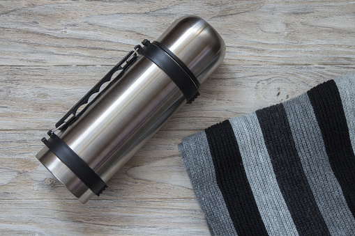 Thermos flask made of stainless steel on a woden background. Top view