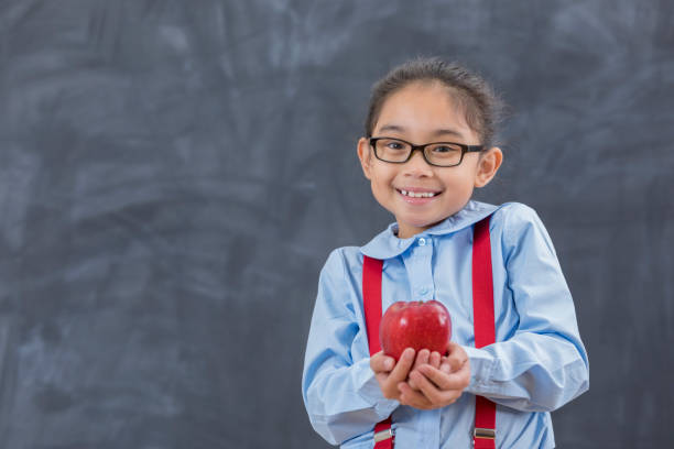 Little cute girl eat red ripe apple. Happy smiling preschool child with satchel holding fresh bio fruits. Apples from harvest