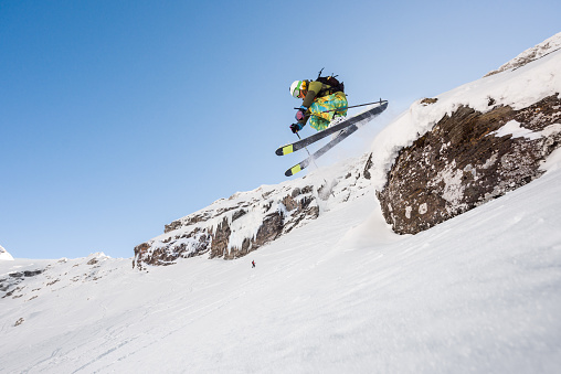 Low angle view of male skier freeriding on craggy steep slope