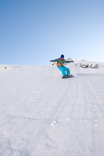 Man riding snowboard downhill ski slope on a bright day