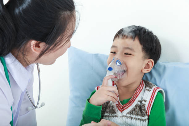 asiatische junge mit erkrankung der atemwege durch arzt mit inhalator geholfen. - asthmatic child asthma inhaler inhaling stock-fotos und bilder