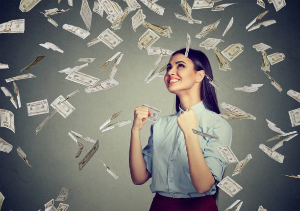 Portrait happy woman Portrait happy woman exults pumping fists ecstatic celebrates success under a money rain falling down dollar bills banknotes isolated on gray wall background with copy space free bingo stock pictures, royalty-free photos & images