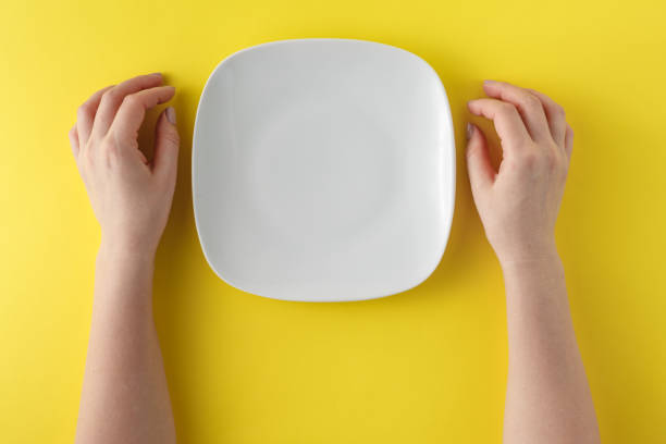 istock Female hands and empty plate on bright yellow 661833038
