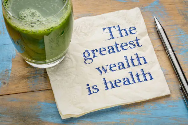 The greatest wealth is health advice or reminder - handwriting on a napkin with a glass of fresh, green, vegetable juice