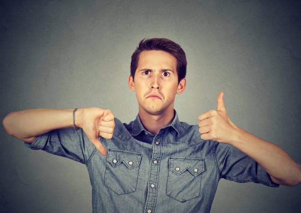 istock Perplexed man with thumbs down thumbs up gesture 661884448
