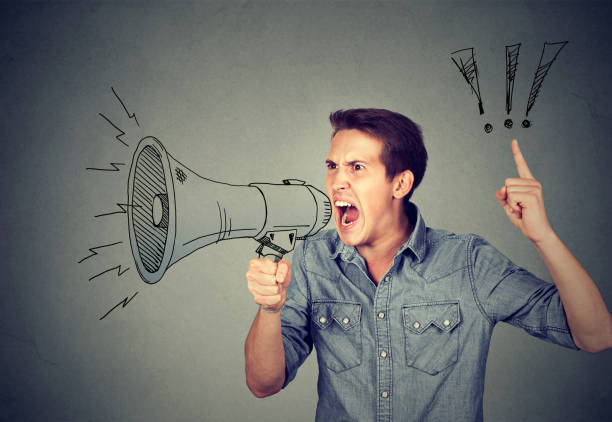 istock Side portrait angry young man holding screaming in megaphone 661885962