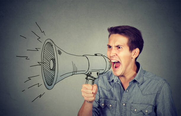 istock Side portrait angry young man holding screaming in megaphone 661885980