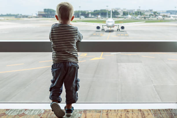 w hali lotniska dziecko patrzy na samolot przez okno - one baby boy only zdjęcia i obrazy z banku zdjęć