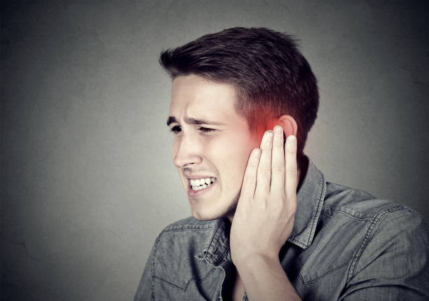 Closeup up side profile sick male having ear pain Tinnitus. Closeup up side profile sick male having ear pain touching his painful head isolated on gray background neuralgia stock pictures, royalty-free photos & images