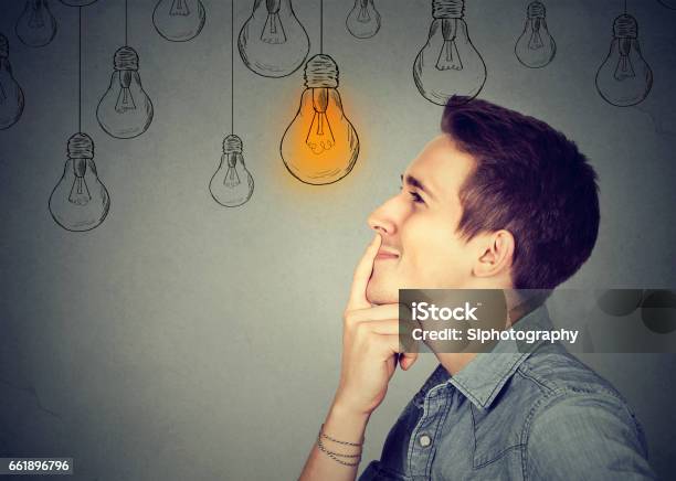Thinking Man Looking Up With Light Idea Bulb Above Head Isolated On Gray Wall Background Stock Photo - Download Image Now