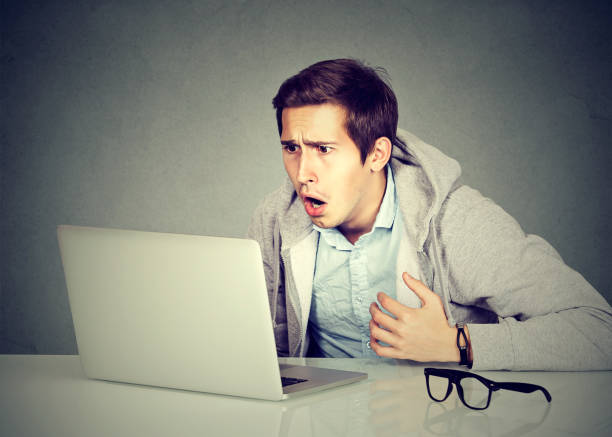 istock Portrait young shocked man with laptop computer sitting at table 661897124