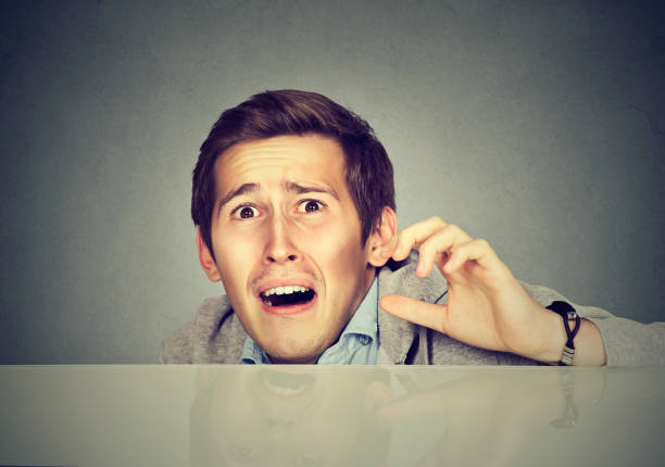 istock Funny scared man peeking from behind the desk isolated on gray background 661897174