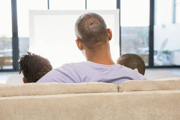 istock Two children sitting on sofa with their father 661904630