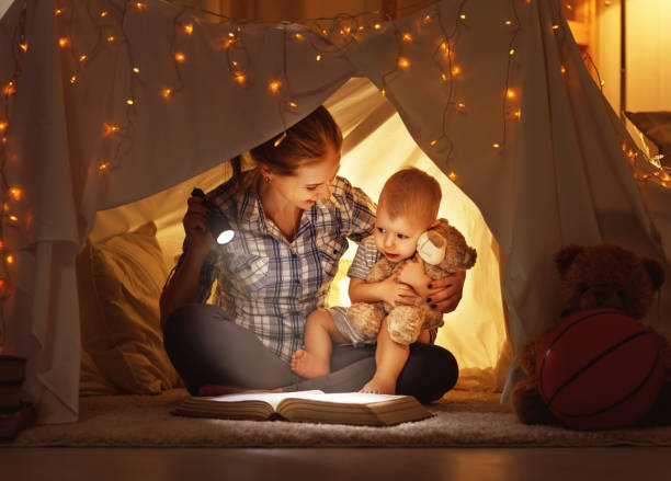 istock mother and child daughter with a book and a flashlight before going to bed 661930906