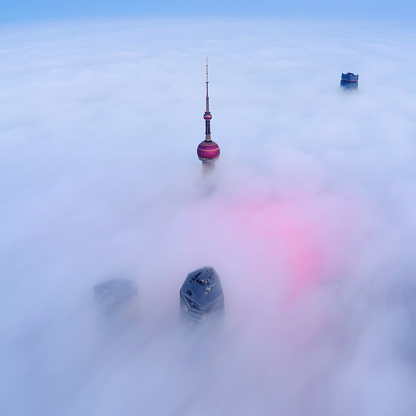 Aerial view of Oriental Pearl Tower and skyscraper in the thick fog at sunrise, China.